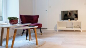 A modern living room with a red chair, a white TV stand, and a small table with a plant. - Casafamilia - Nantes Bord de Loire (Rezé)