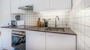 A modern kitchen with white cabinets, a stainless steel sink, a microwave, and a dishwasher. - Casafamilia - Nantes Bord de Loire (Rezé)