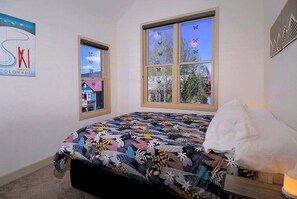 A bedroom with a bed, a window with a view, and a wall with a poster. - Horseshoe Haven, Immaculate 2BD/2BA, Pet friendly! (Mt. Crested Butte)