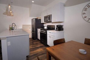 A compact kitchen with a refrigerator, stove, microwave, and a clock on the wall. - Horseshoe Haven, Immaculate 2BD/2BA, Pet friendly! (Mt. Crested Butte)