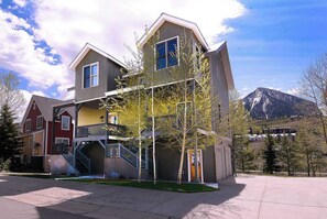 A multi-story building with a balcony, a staircase, and a mountain in the background. - Horseshoe Haven, Immaculate 2BD/2BA, Pet friendly! (Mt. Crested Butte)