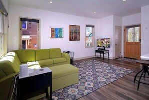 A living room with a green sofa, a television, and artwork on the walls. - Horseshoe Haven, Immaculate 2BD/2BA, Pet friendly! (Mt. Crested Butte)