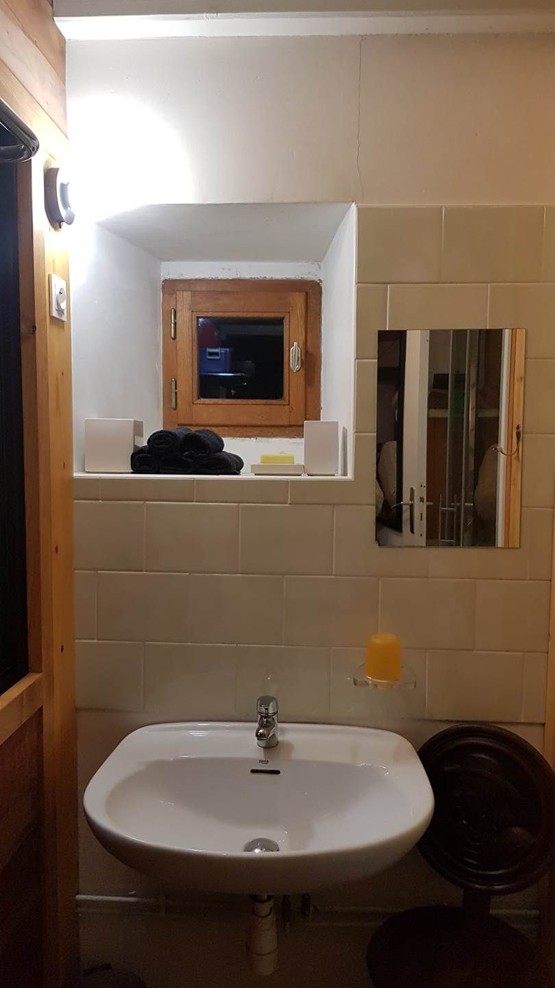 A bathroom with a sink, a mirror, a wooden cabinet, and a microwave.