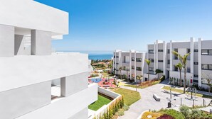 Un edificio moderno con zona de piscina, que incluye un área de juegos infantiles y un pequeño jardín.