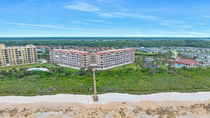 Une station balnéaire comprenant plusieurs bâtiments d’hôtel, une plage et une jetée qui s’avance dans l’océan.