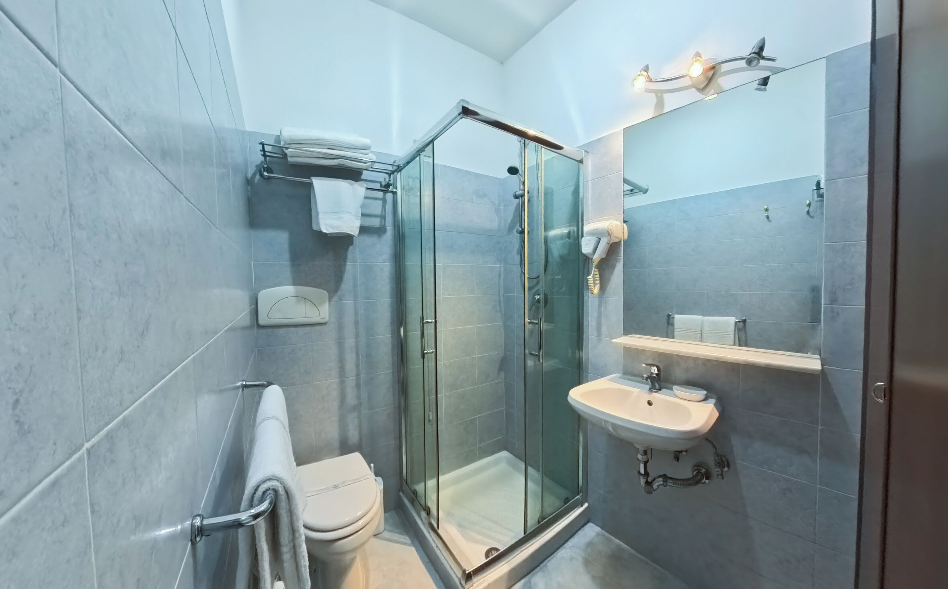 Een moderne badkamer met een glazen douchecabine, toilet, wastafel en handdoekrek.