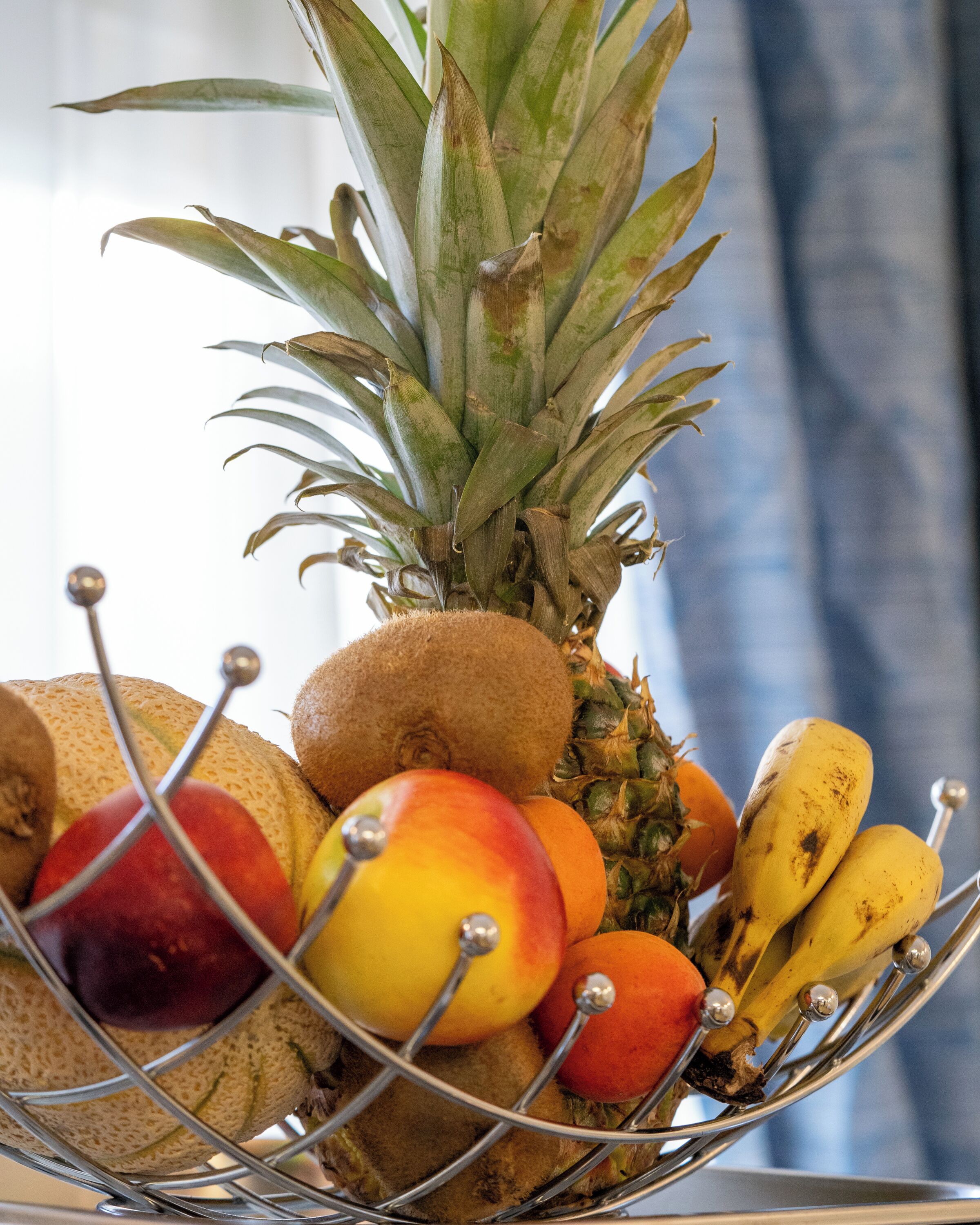 Un panier de fruits contenant un ananas, des bananes, des pommes et une noix de coco.
