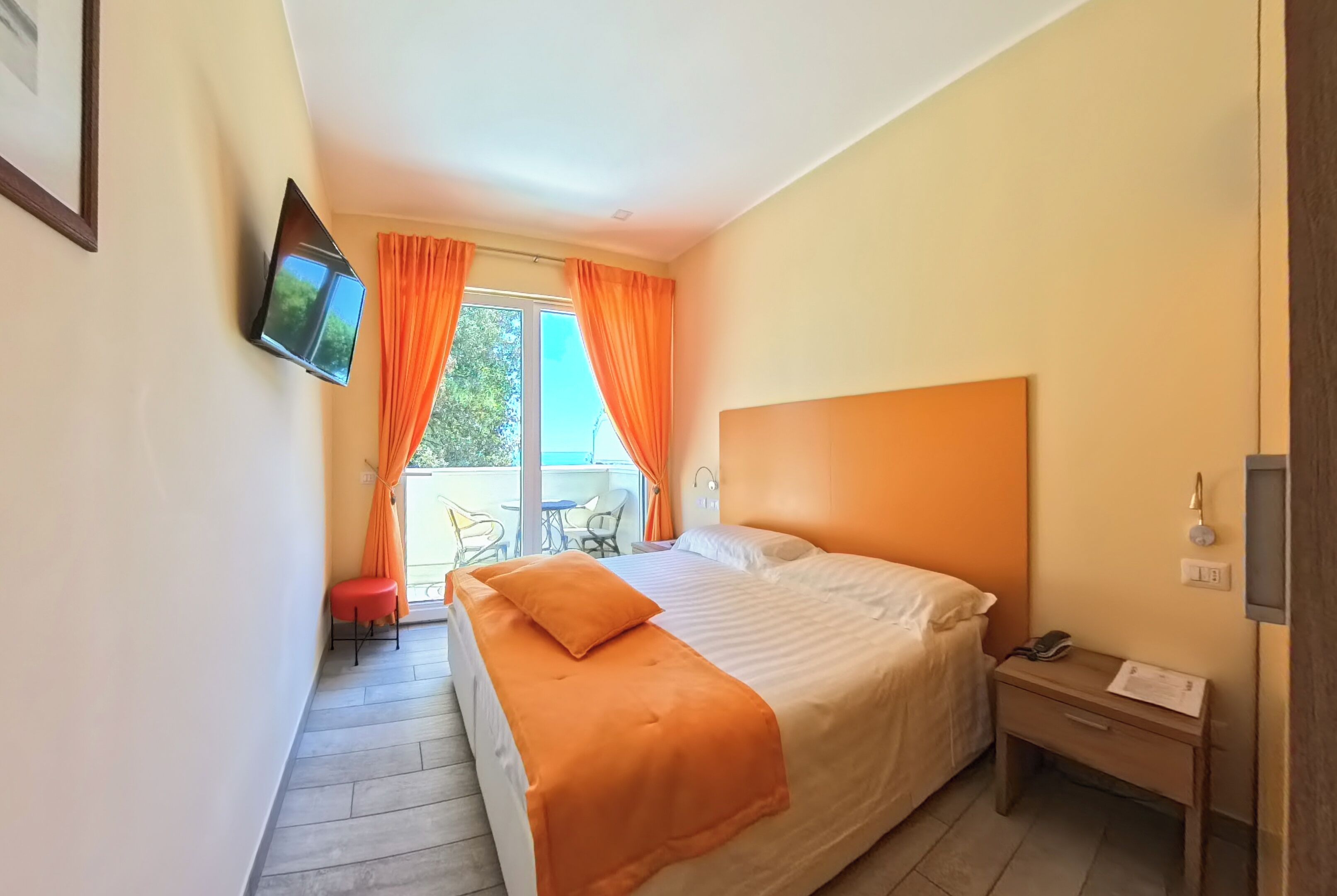 A hotel room with a bed, a desk, a chair, and a TV mounted on the wall.