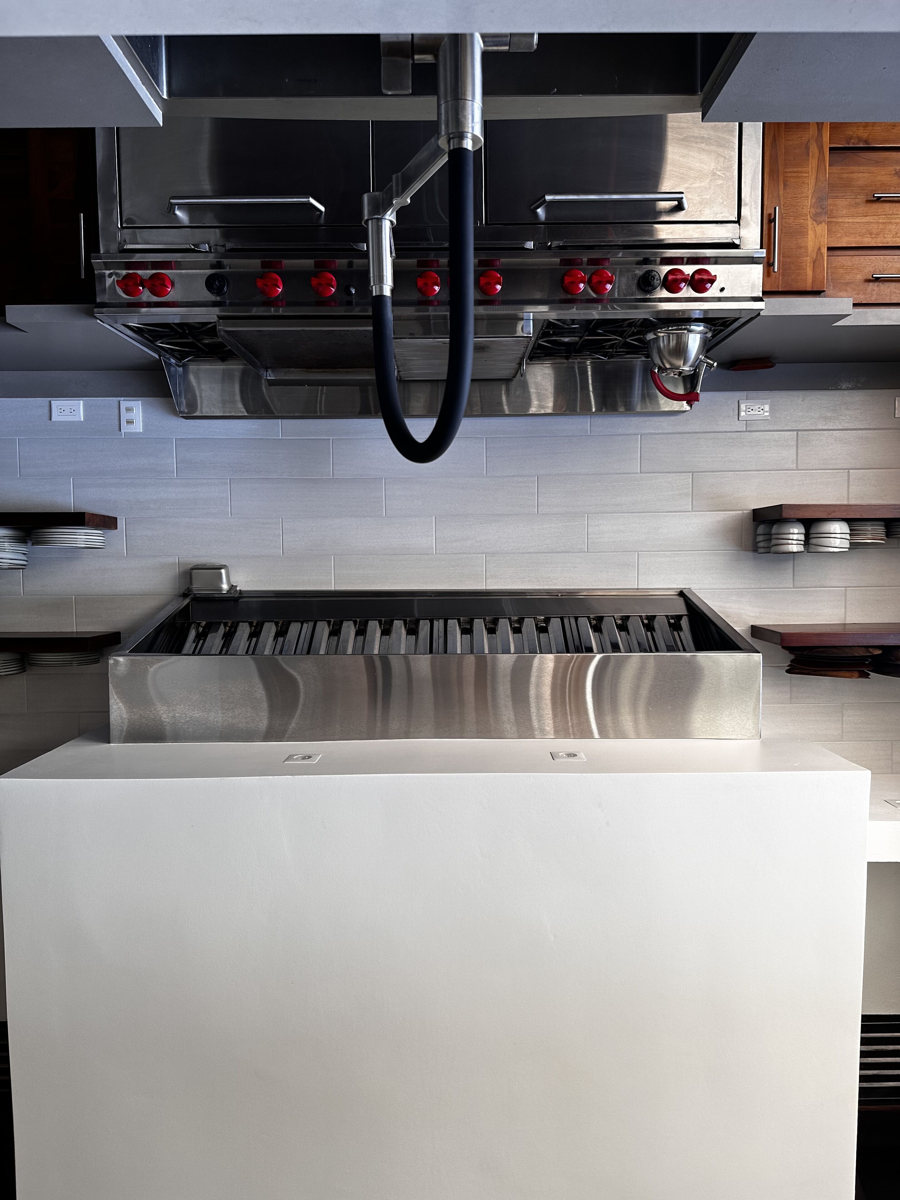 Una cocina con campana extractora de acero inoxidable, horno empotrado y placa de cocción de acero inoxidable.