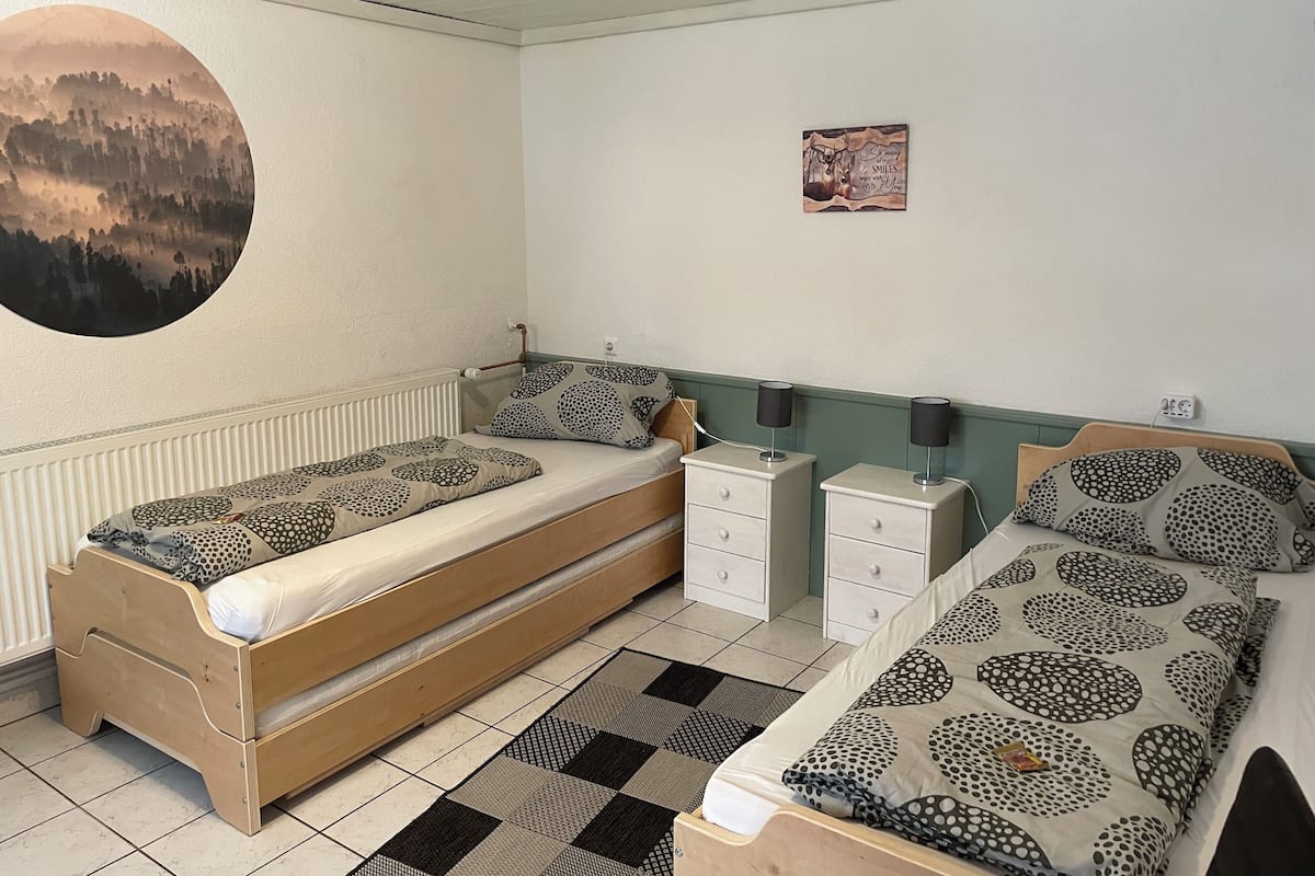 A bedroom with two beds, a radiator, a wall clock, and a motivational poster.