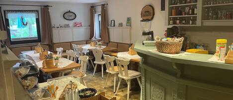 A cozy restaurant with wooden furniture, a buffet setup, and a bar area.