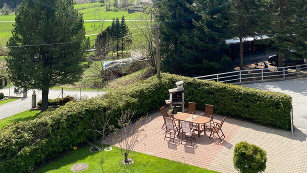 A patio with a table and chairs, surrounded by greenery and a mountain view. - Molltaler Appartements  (Stall)