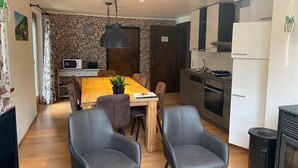 A compact living space with a dining area, kitchen, and a small seating area with two chairs. - Molltaler Appartements  (Stall)