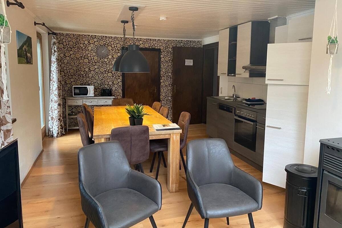 A compact living space with a dining area, kitchen, and a small seating area with two chairs.