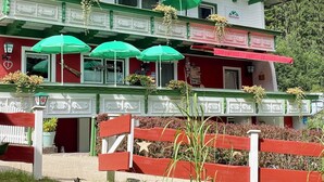 A multi-story building with green and white exterior, balconies with flower arrangements, and outdoor umbrellas. - Molltaler Appartements  (Stall)