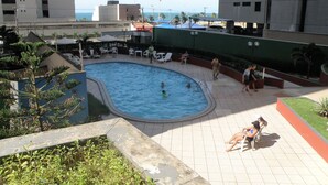A rooftop pool area with a view of the ocean, surrounded by lounge chairs and umbrellas. - Porto de Iracema Apartamentos (Fortaleza)