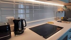 Et moderne køkken med en sort induktionskogetop, elkedel og brødrister.