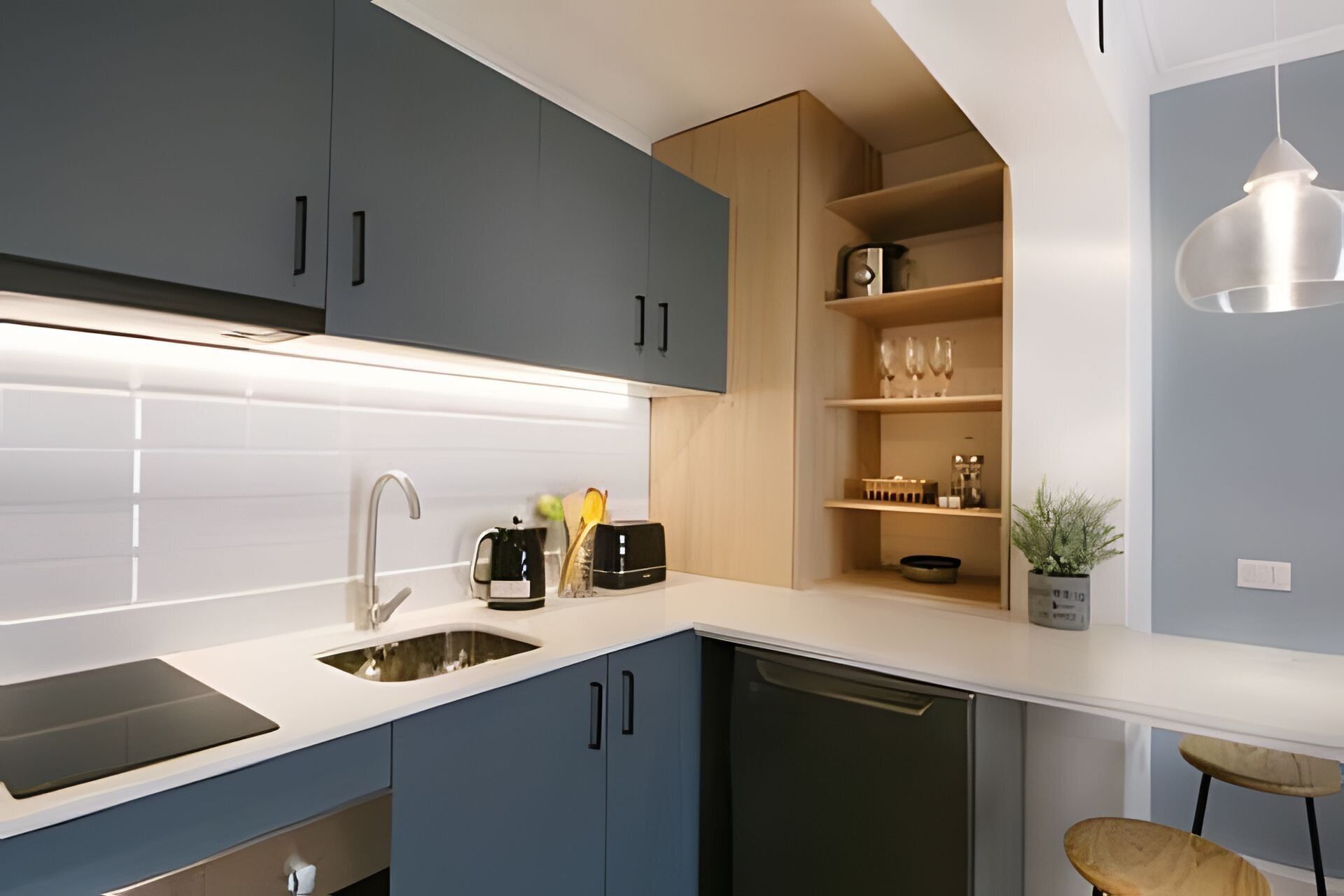 Een moderne keuken met grijze kastjes, een wit aanrecht en een ingebouwde vaatwasser.