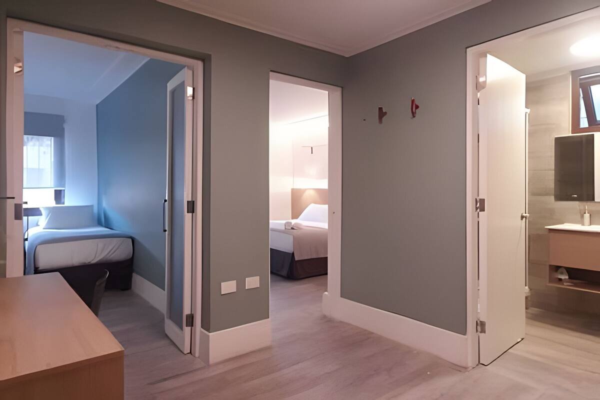 A hotel room with a bed, a desk, and a bathroom with a mirror and sink.