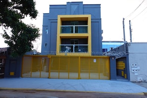 Un bâtiment avec une porte de garage jaune, une façade bleue et jaune, et une fenêtre grillagée.
