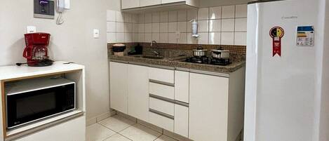 Suite | Privékeuken | Een magnetron, een kookplaat, kookgerei, borden en bestek, een vriezer