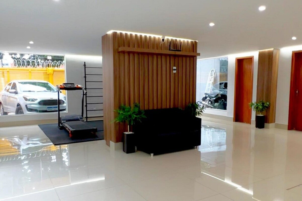 A modern lobby with a reception desk, a black sofa, and a wooden panel wall.
