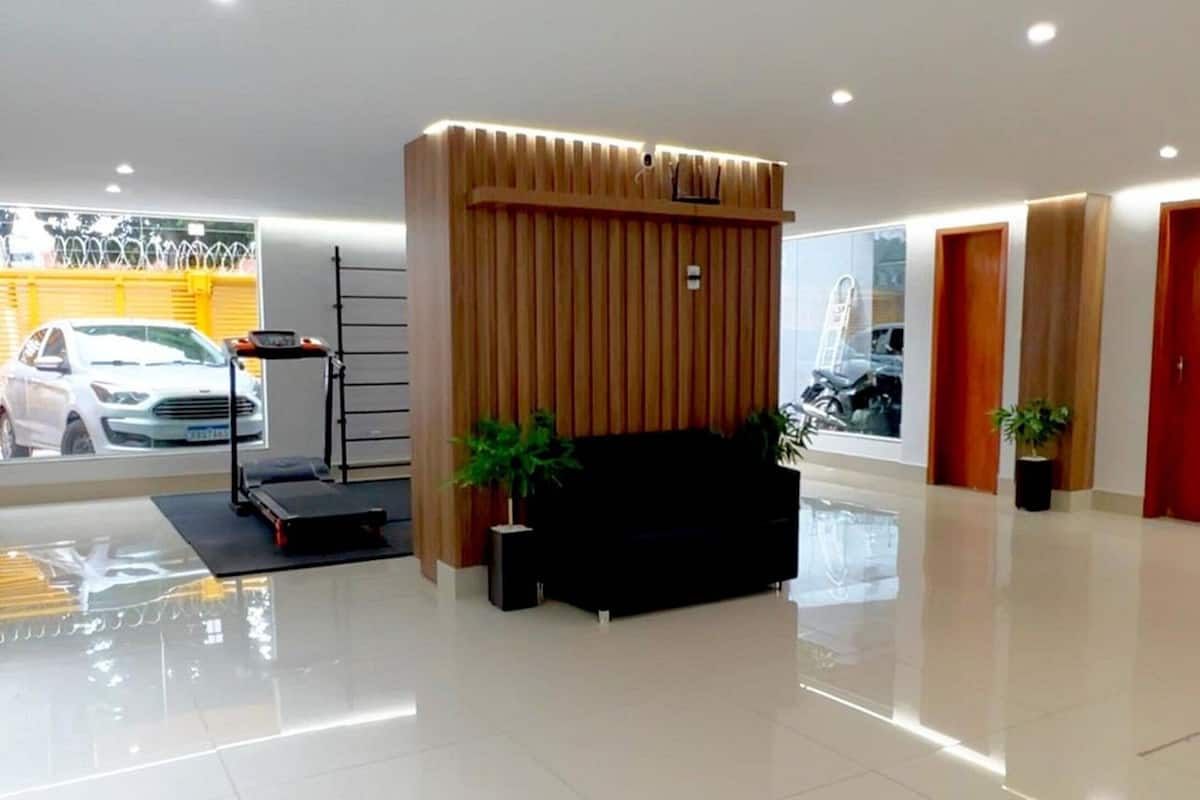 Um lobby moderno com um balcão de atendimento, um sofá preto e uma parede de painéis de madeira.