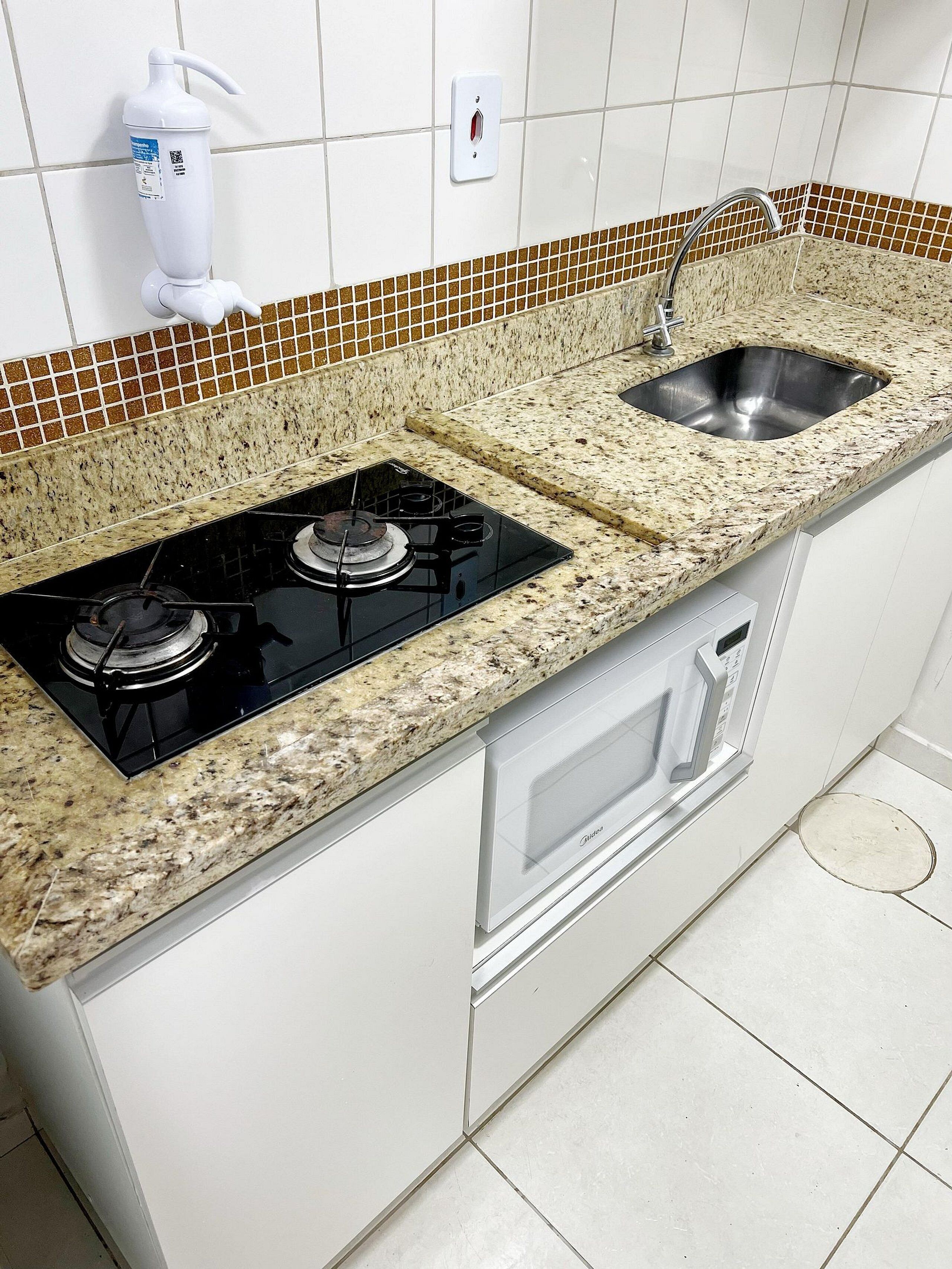 Eine Küche mit Granitarbeitsplatte, Edelstahlspüle und eingebautem Backofen.