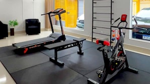 A gym with exercise equipment, a bench, and a window with a view of the outside. - Residencial Carajás (Goiania)