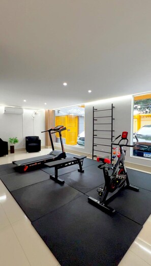 A gym with exercise equipment, a bench, and a window with a view of the outside. - Residencial Carajás (Goiania)