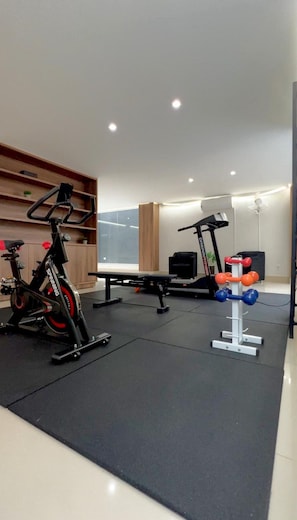 Une salle de sport équipée de vélos d’exercice, d’un tapis de course et d’haltères.