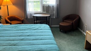 A hotel room with a large bed, a small table, two chairs, a lamp, and a window with curtains. - Grand Lake Hotel (Lebanon)