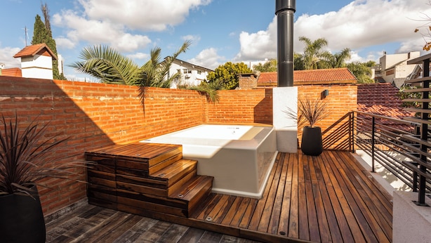 A rooftop deck with a hot tub, wooden steps, and a brick wall. - LUXURY HOUSE VILLA DEVOTO (Buenos Aires)