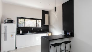 A modern kitchen with white cabinets, a black countertop, and a window providing natural light. - LUXURY HOUSE VILLA DEVOTO (Buenos Aires)