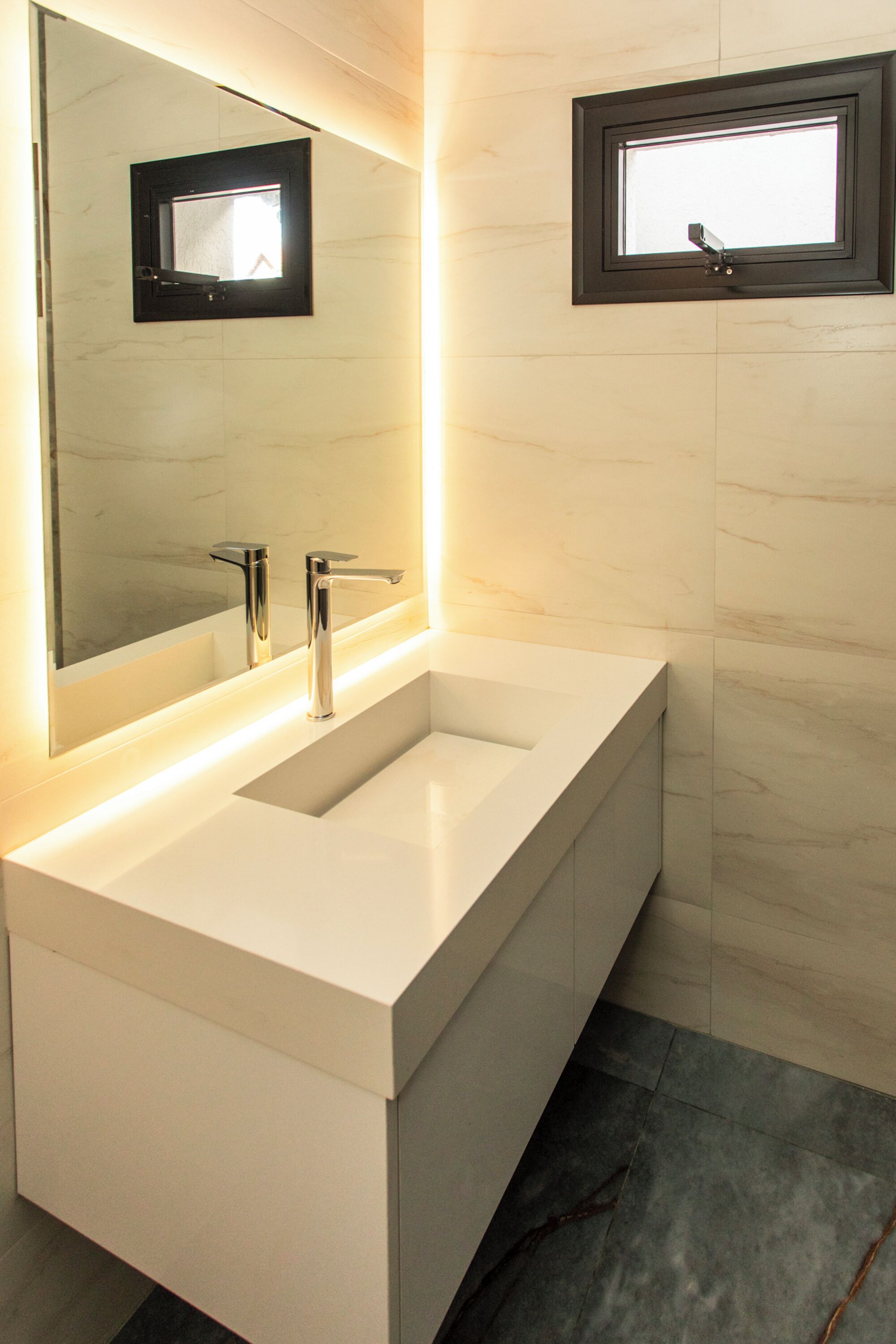 Un baño moderno con tocador blanco, dos lavabos, un espejo grande y un ventanal.