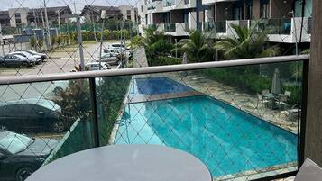 Un balcón con vista a la piscina, una mesa y sillas.