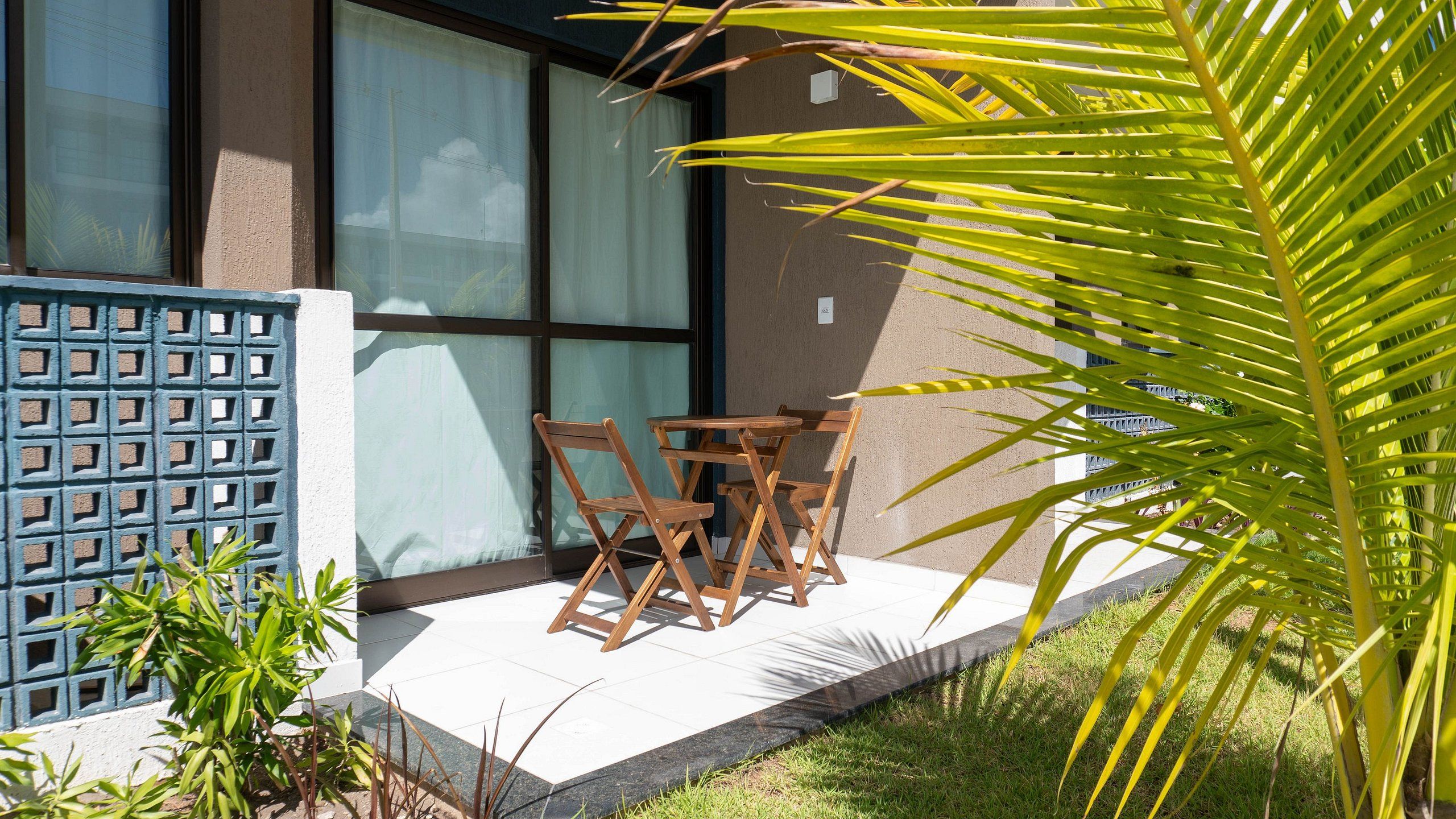 Un patio con una mesa y sillas, una cerca azul y una palmera.