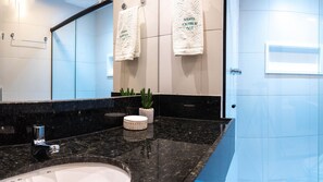 A modern bathroom with a black marble countertop, a white sink, two potted plants, and two towels hanging on the wall. - Makia Beach Experience Porto de Galinhas (Ipojuca)