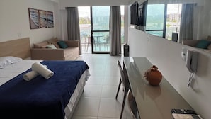 Habitació d'hotel amb llit, escriptori, cadira, televisió i una finestra gran amb vistes.