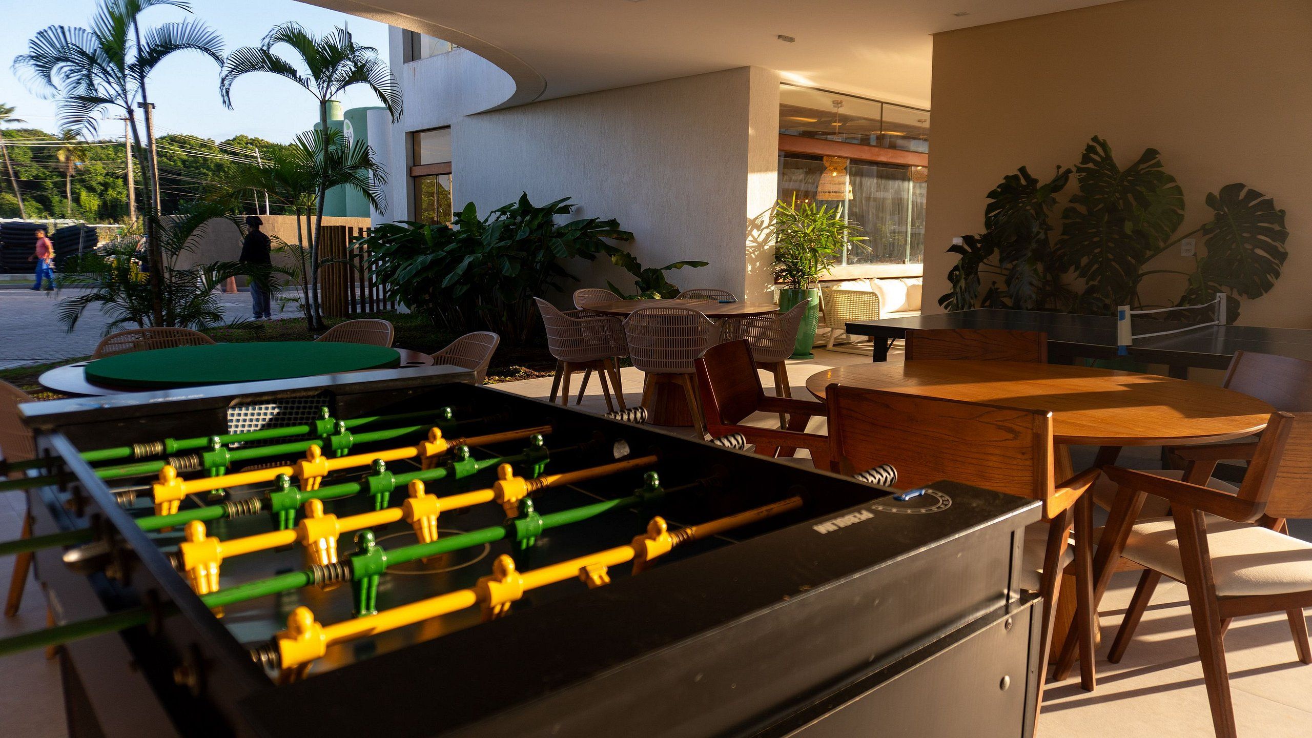 An outdoor seating area with a foosball table, chairs, and tables.