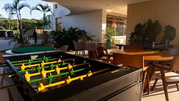 An outdoor seating area with a foosball table, chairs, and tables.