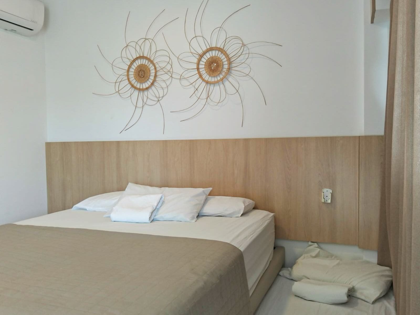 A hotel room with a bed, pillows, a headboard, and wall art.