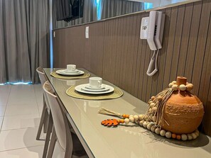 A dining area with a long table set for two, a telephone, and a decorative vase. - Makia Beach Experience Porto de Galinhas (Ipojuca)
