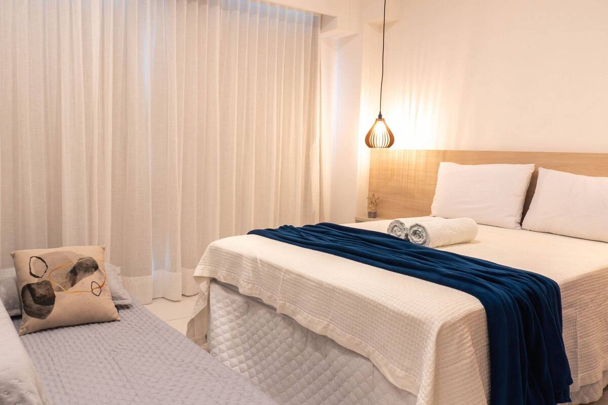 A hotel room with a large bed, a smaller bed, and a nightstand with a lamp.