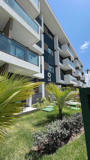 A modern multi-story building with balconies and a sign that reads "LÁ". - Makia Beach Experience Porto de Galinhas (Ipojuca)