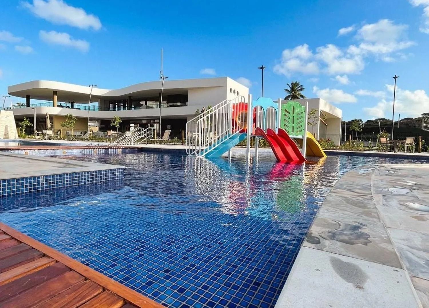 A swimming pool with a slide, a covered area, and a building with a modern design.