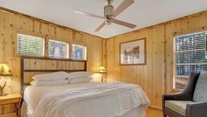 A bedroom with a bed, a chair, a ceiling fan, and wooden walls. - 5 Bedroom, 2 Bath Cabin. 2 Kings, 3 Queens. Full Kitchen, living/dining room. (South Lake Tahoe)