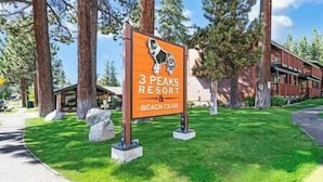 A sign for 3 Peaks Resort & Beach Club with a dog illustration.