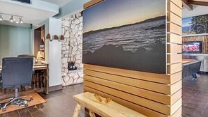 A room with a large painting of a seascape, a wooden bench, and a stone wall.