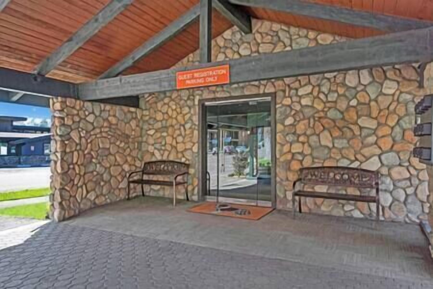 Un edificio de piedra con un cartel que dice “RESORT PRIVADO SOLAMENTE” y dos bancos afuera.